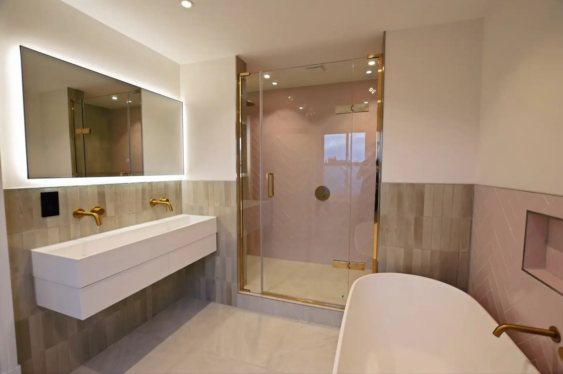 Backlit mirror and basin with brushed brass taps, daughter's ensuite
