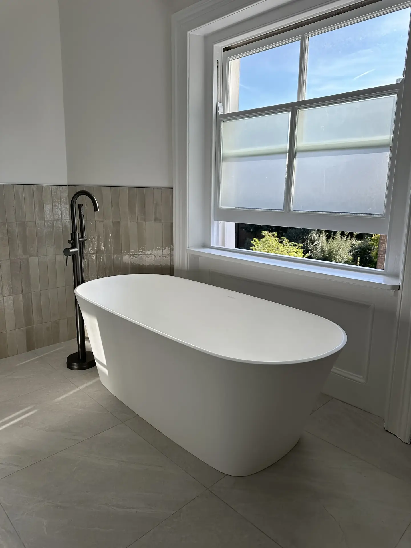 Freestanding bath with matte black filler in natural light, son's ensuite