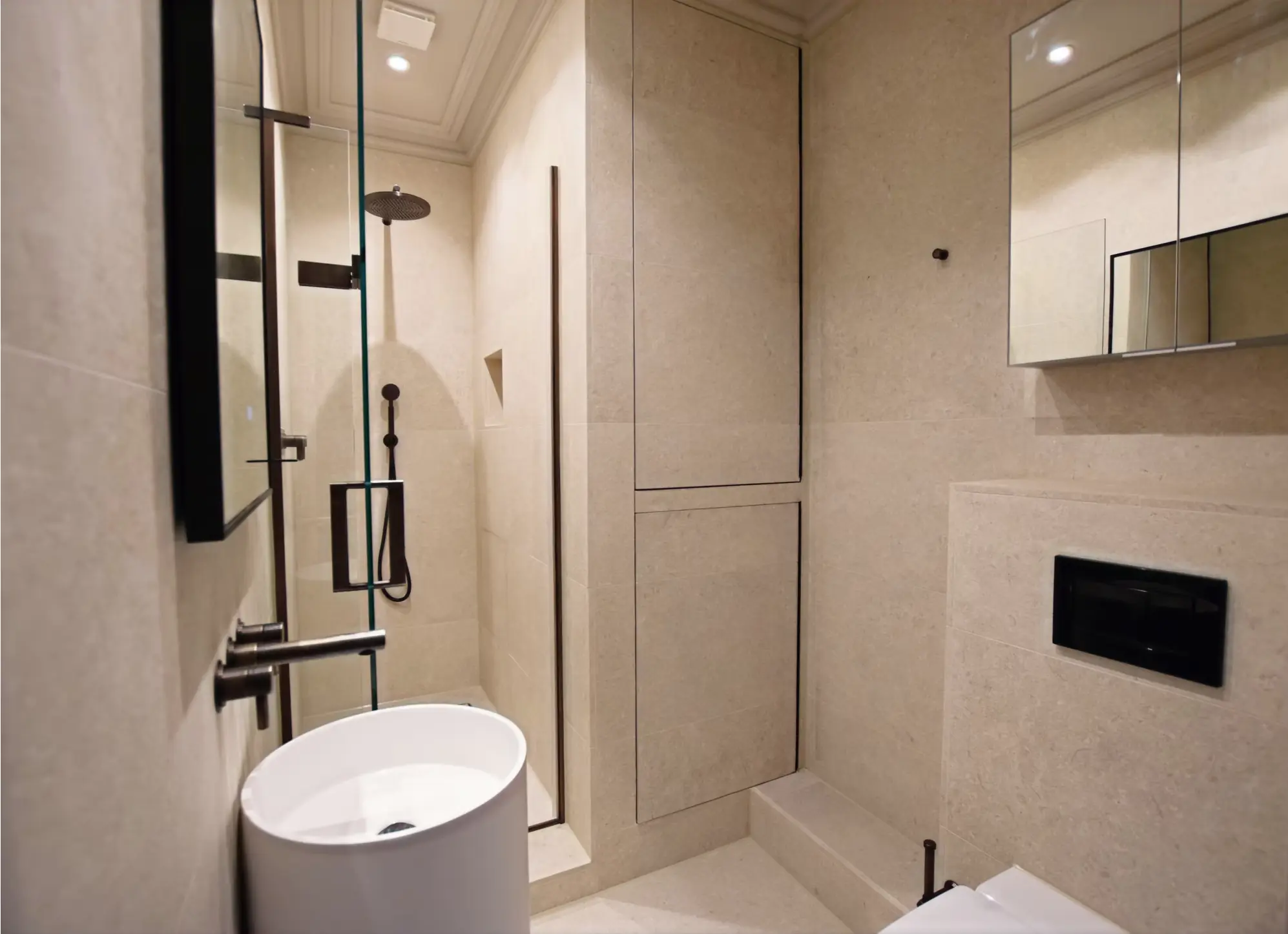 Luxury ensuite bathroom with pedestal basin, shower enclosure and stone tiles, London