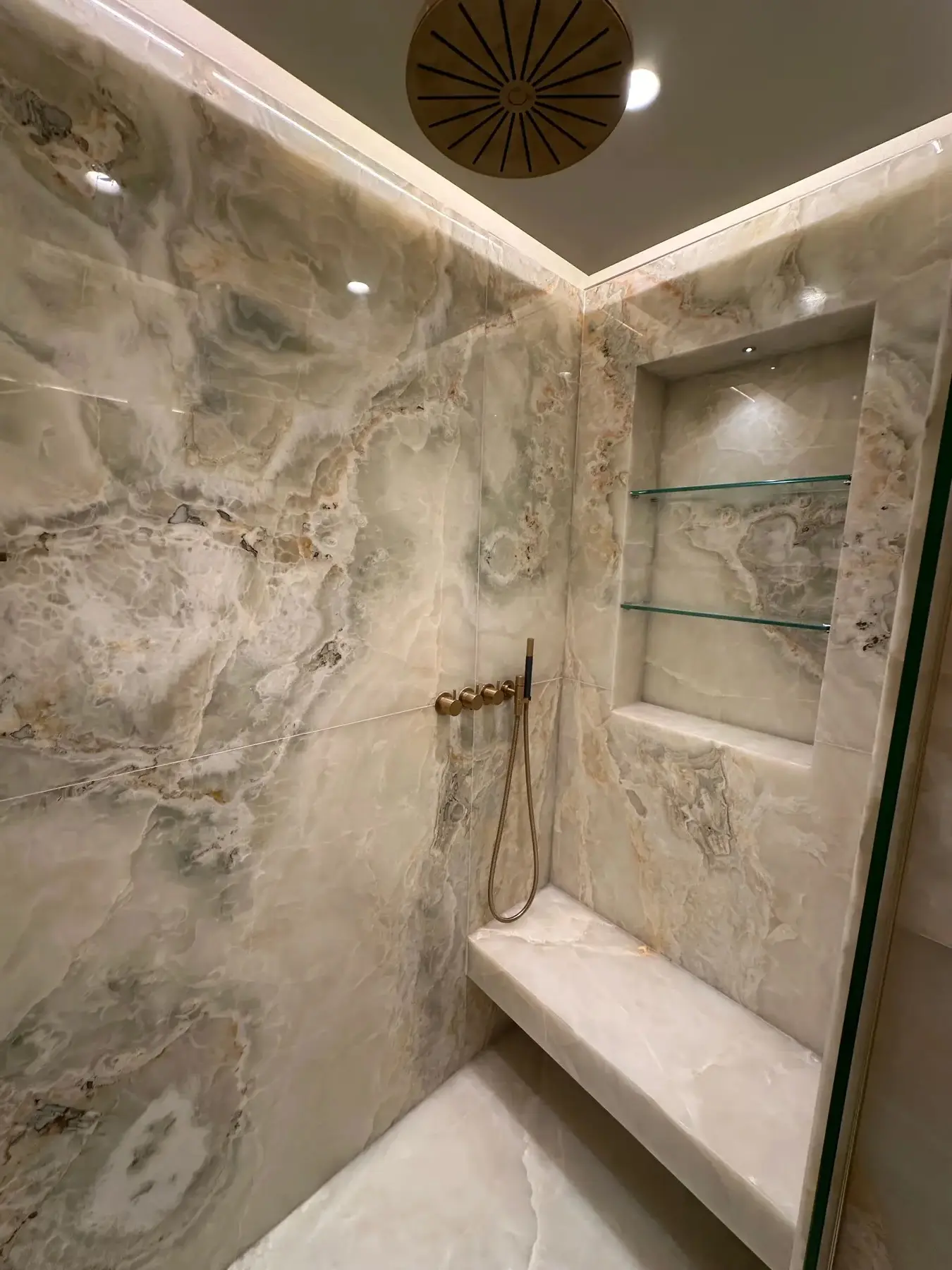 Master ensuite onyx shower interior with brass rain head and recessed niche - Holland Park apartment