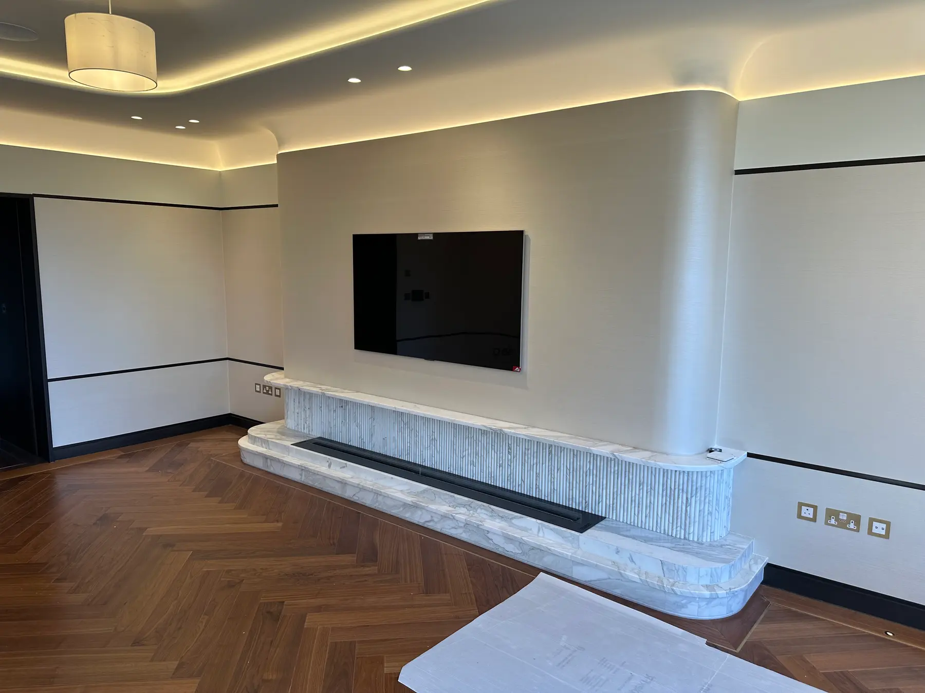 Fluted marble fireplace plinth, wall-mounted TV and herringbone flooring - Holland Park apartment refurbishment