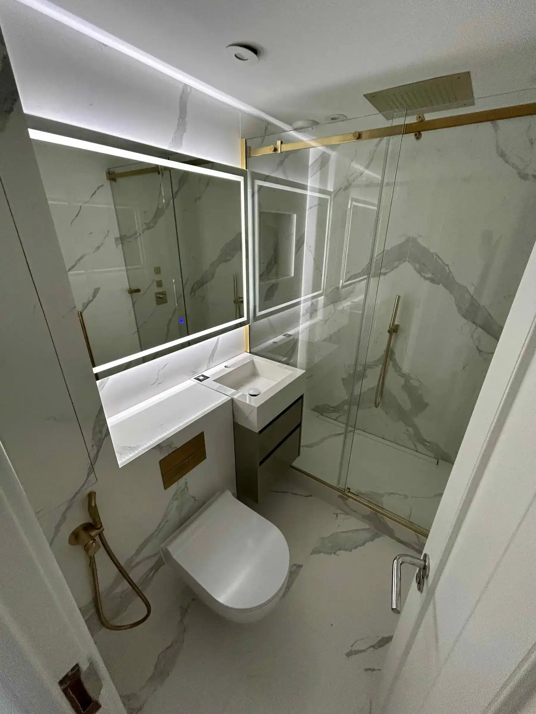 Ensuite bathroom with marble tiling and gold corner shower - Chelsea apartment refurbishment