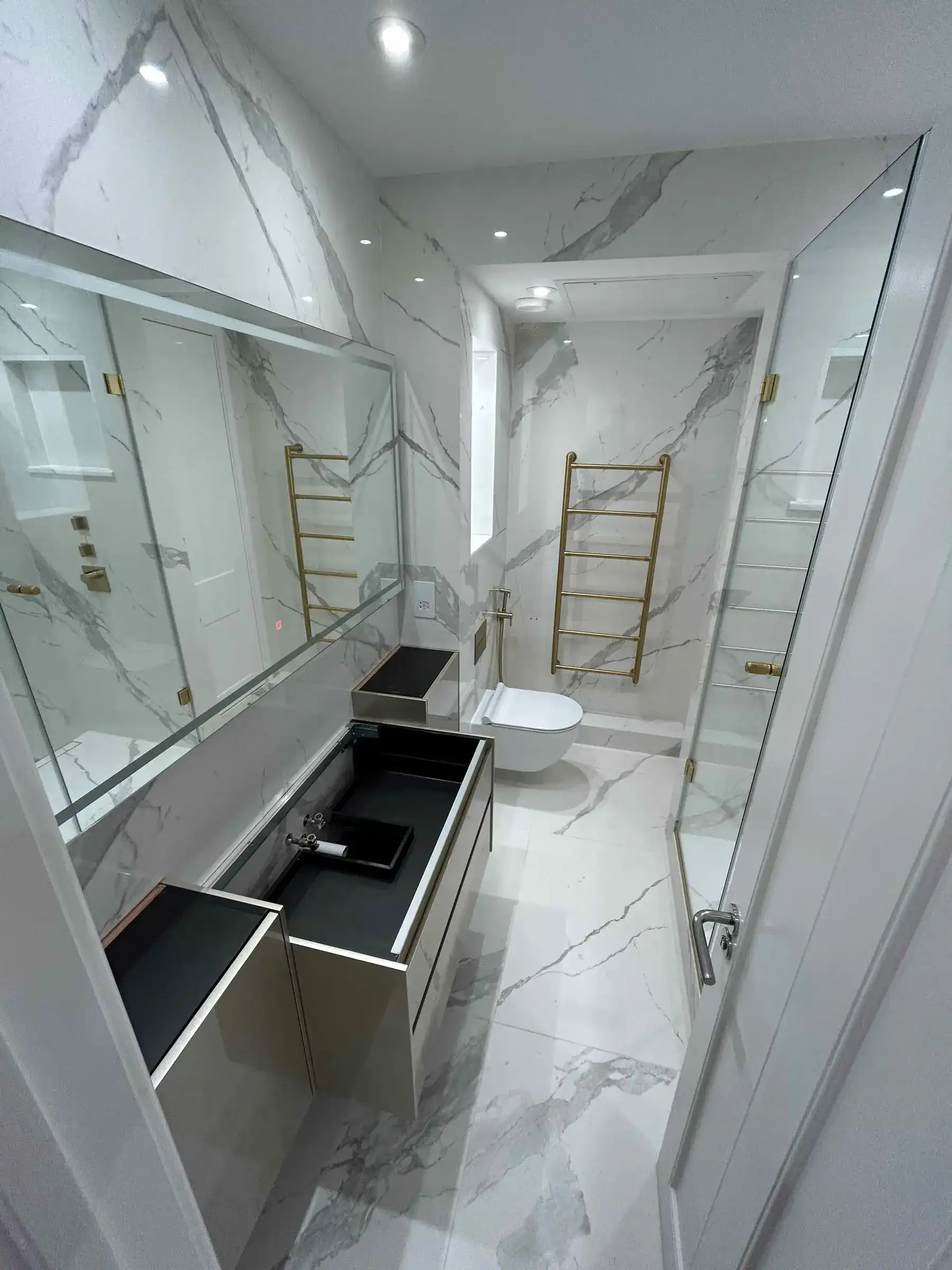 Ensuite with marble tiles and gold towel rail - London apartment Kings Road