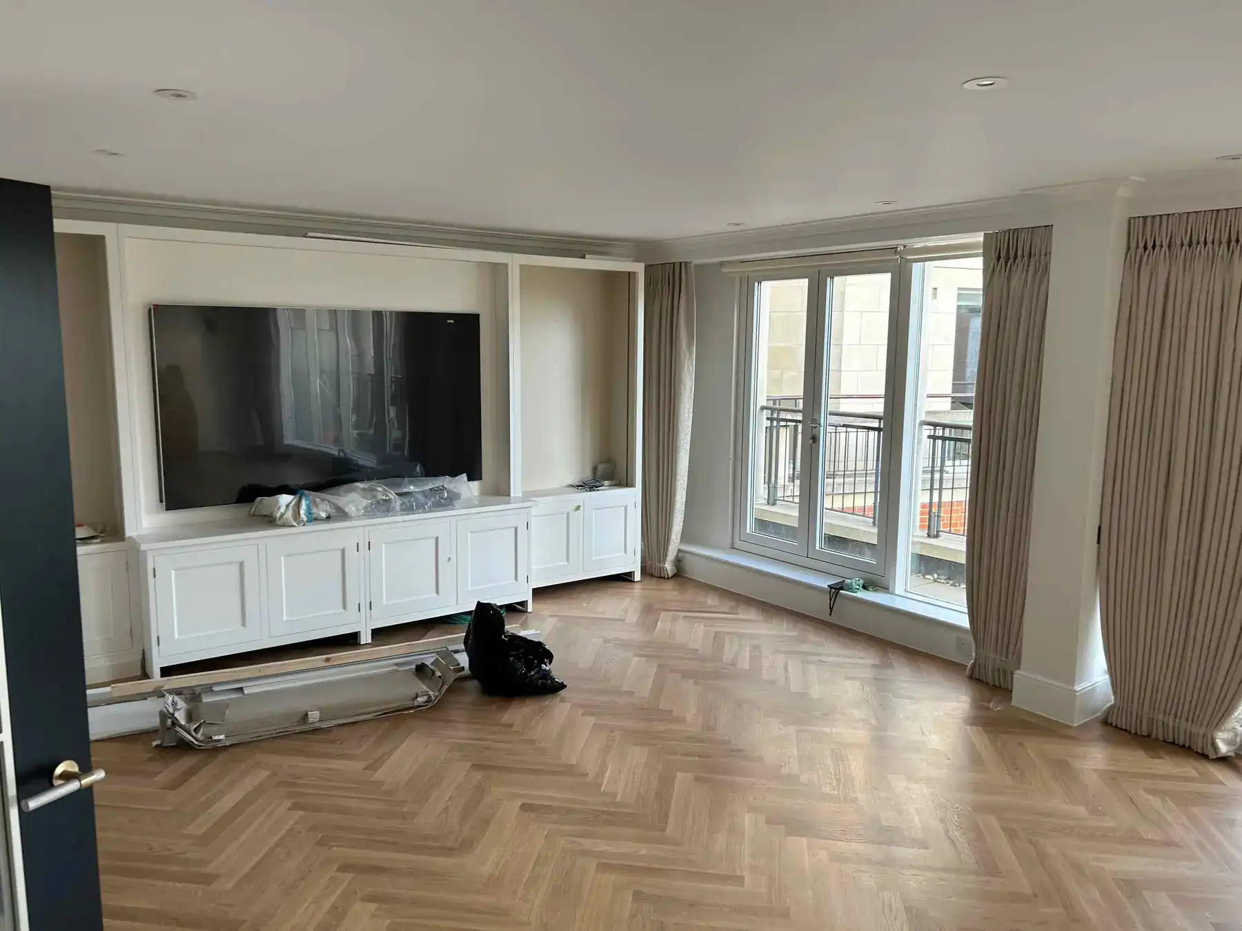Lounge with TV media wall and herringbone flooring - Chelsea apartment refurbishment