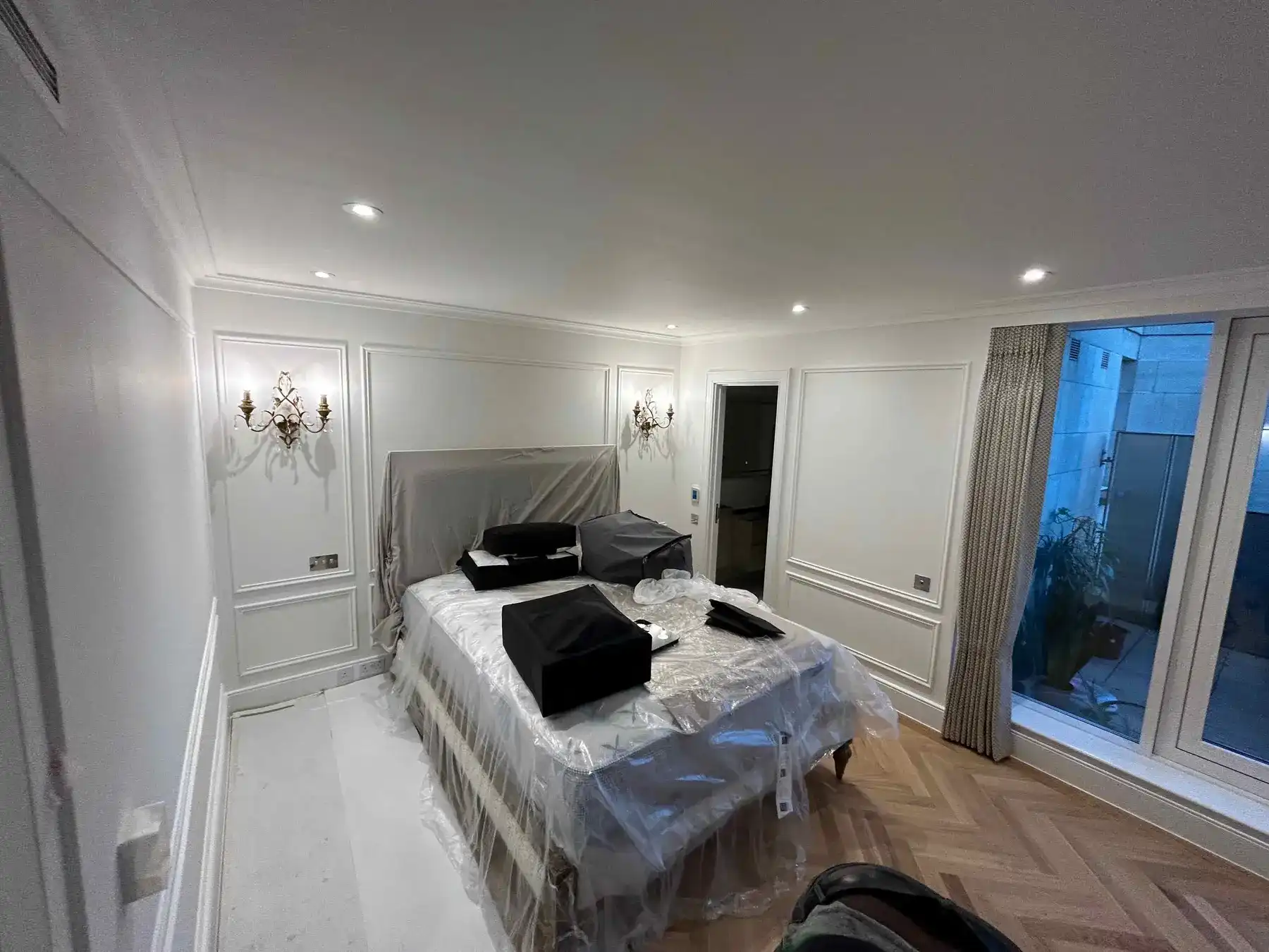 Master bedroom with wall panelling and herringbone flooring - London apartment refurbishment