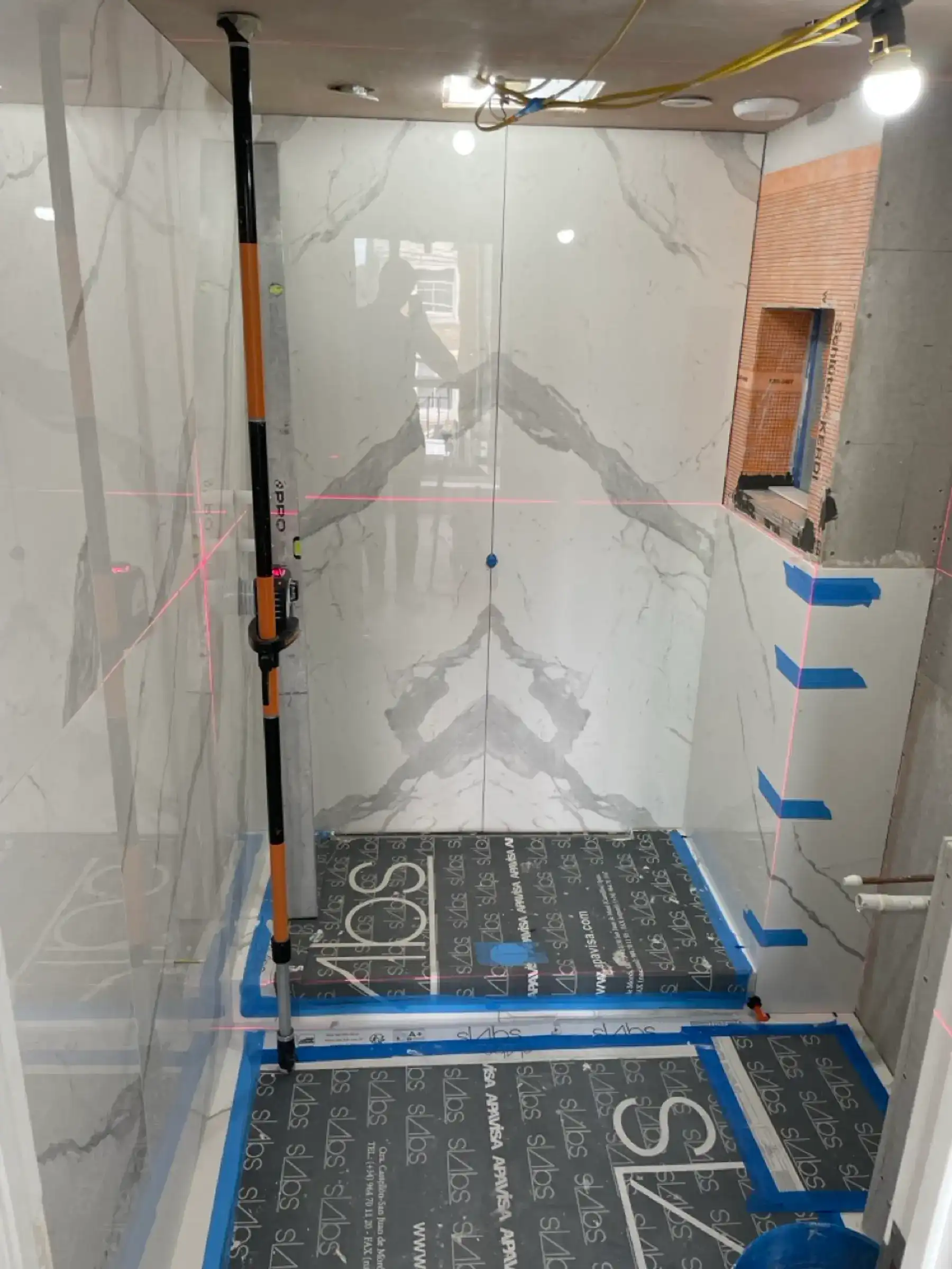 Marble bathroom tiling with laser level - London apartment refurbishment Kings Road