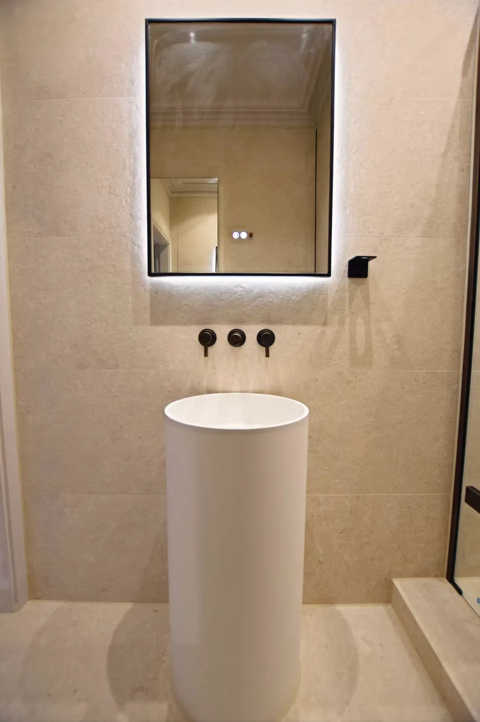 Freestanding cylindrical pedestal basin with backlit black-framed mirror and matte black wall-mounted mixer - South Kensington SW7