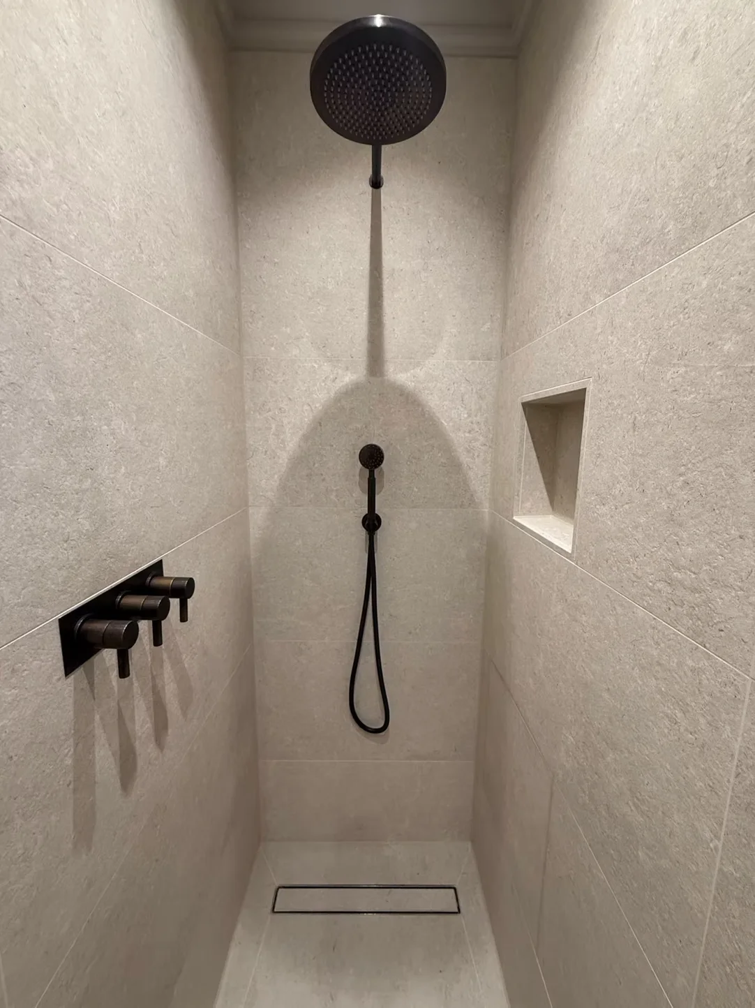 Walk-in shower with large format limestone-effect tiles, matte black rainfall head and linear drain - South Kensington SW7